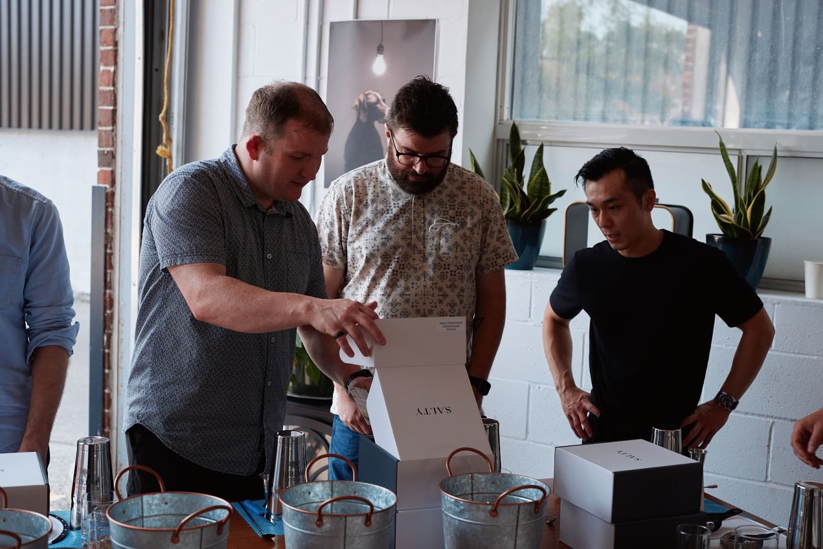 PostBeyond team members gathering around cocktail making kit